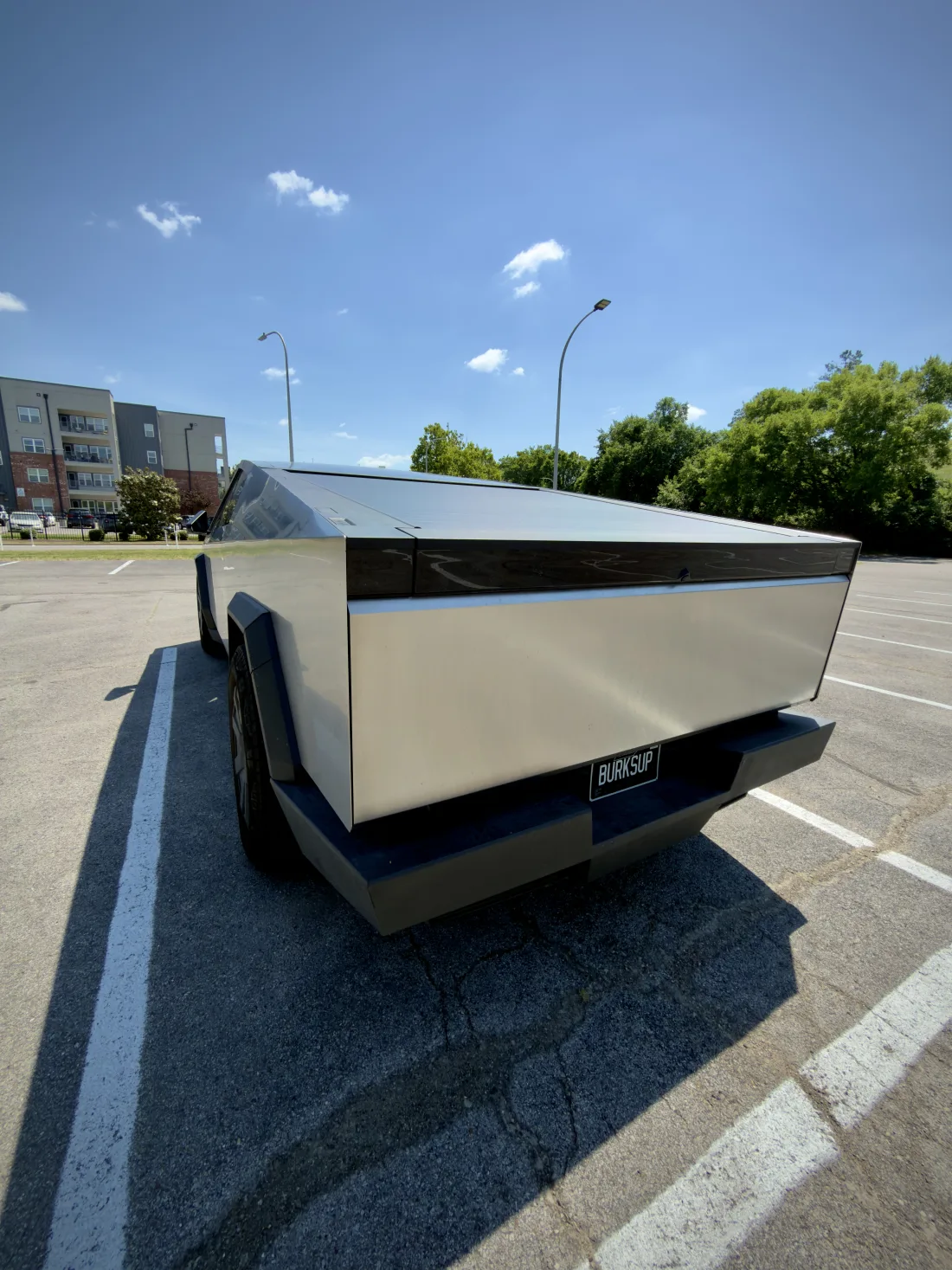 A Tesla Cybertruck in a parking lot with a BURKSUP license plate.