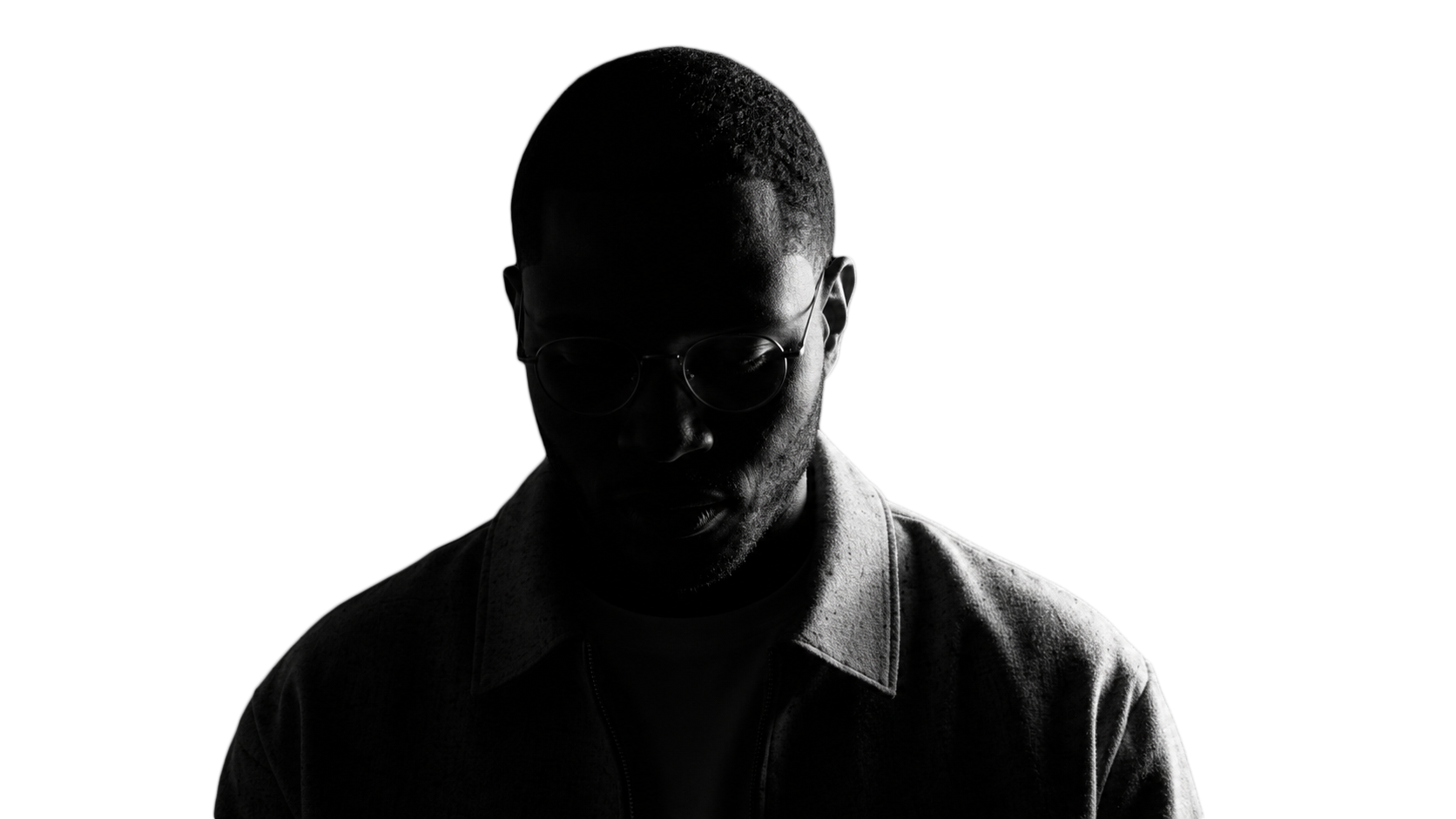 Black-and-white portrait of Nick looking down, wearing glasses and a light jacket.