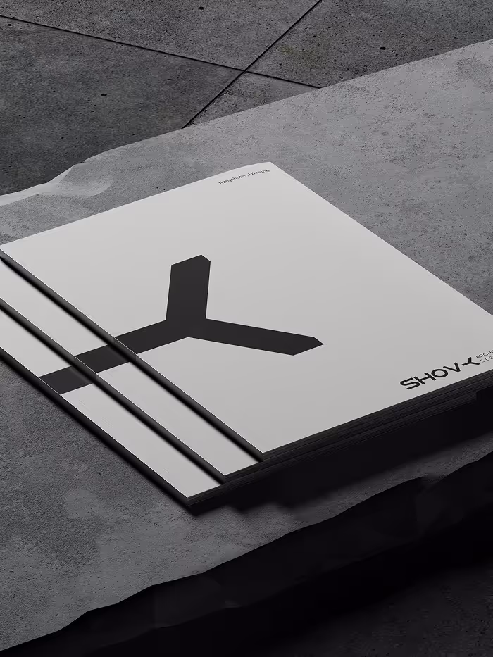 Three stacked minimalistic magazines with a large black K-shaped graphic on the cover, placed on a textured concrete surface.